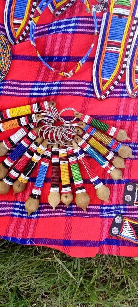 A flat-lay of colourful beaded keychains arranged on a red Maasai shuka