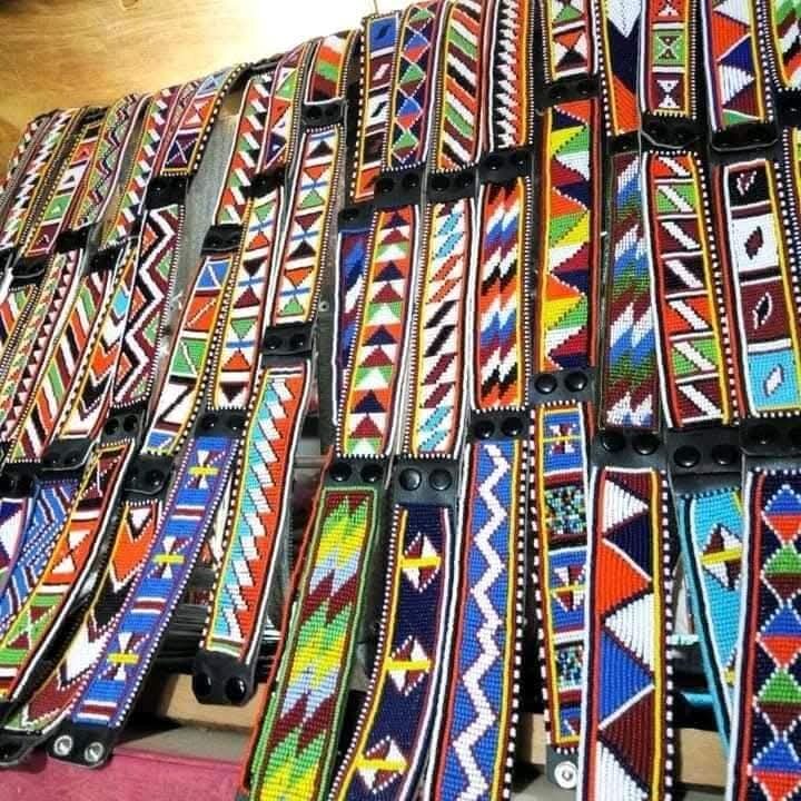 A close-up display of intricately patterned Maasai beaded straps and belts in red, blue, green, and white